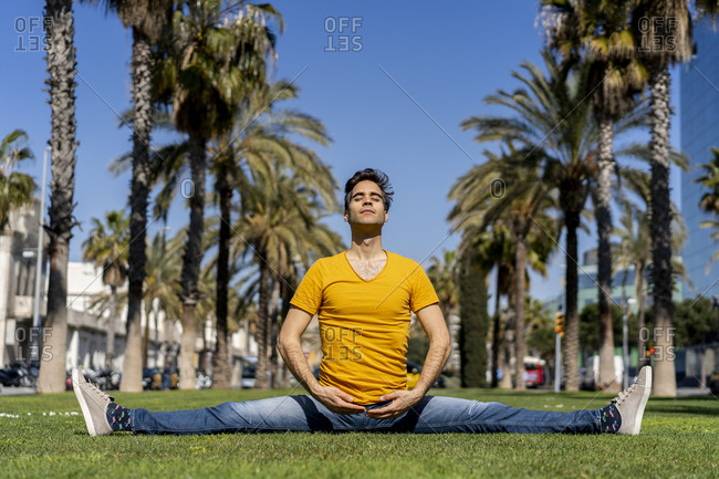 Spain- Barcelona- man practicing yoga on lawn in the city