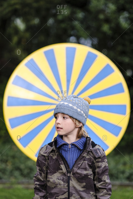 Portrait of boy wearing warm clothing standing in front of yellow and blue circle