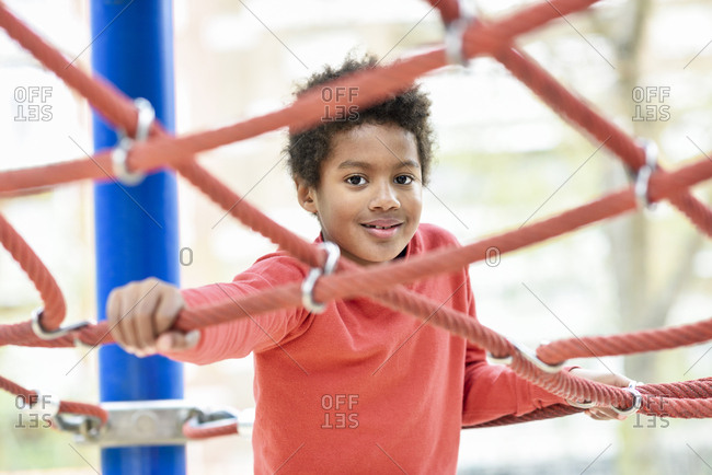 Little boy playing on playground in a park- climbing in a jungle gym