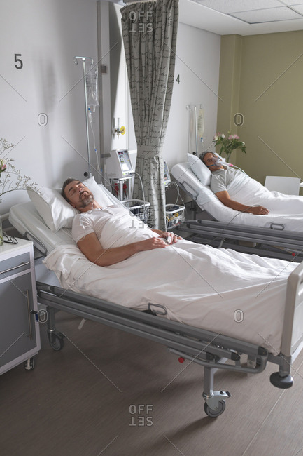 Side view of Caucasian male patients sleeping on bed in the ward at hospital