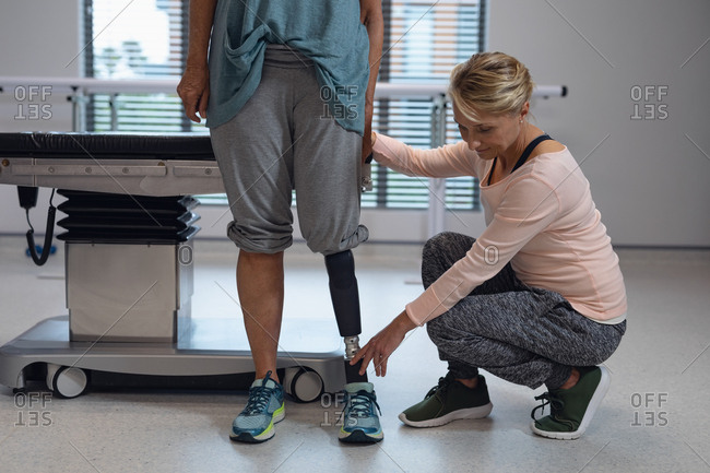 Front view of Caucasian female physiotherapist adjusting prosthetic leg of female patient in hospital