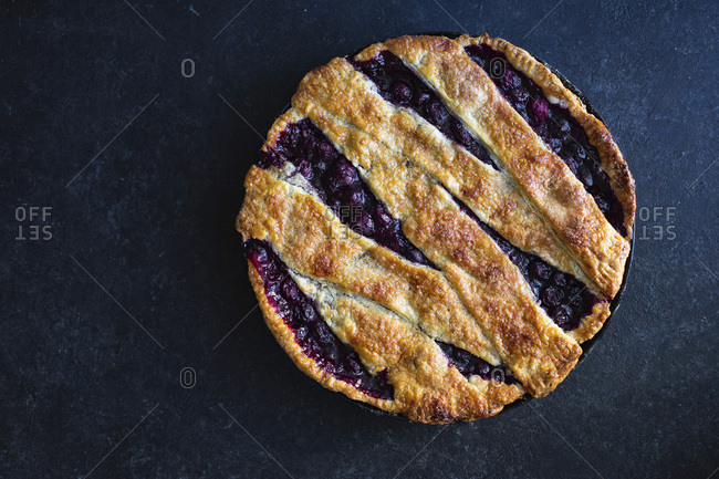 Cherry pie with a lattice and flaky crust shot on blue background