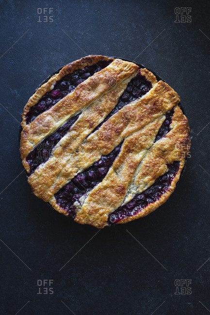 Cherry pie with a lattice and flaky crust shot on blue background