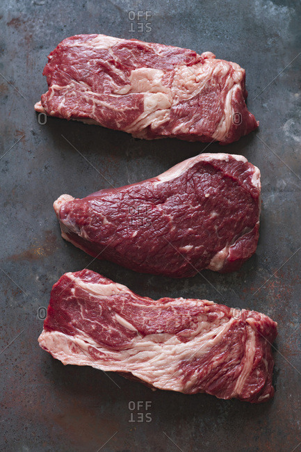 Raw black angus prime beef steak variety on dark metallic background