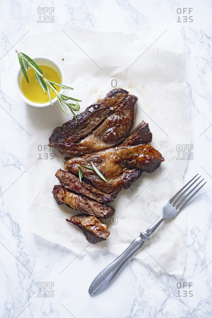 Cooked black angus prime beef steak with rosemary and olive oil on marble surface