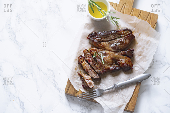 Cooked black angus prime beef steak with rosemary and olive oil on marble surface