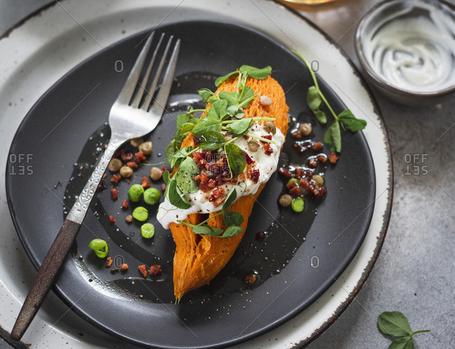 Whole baked sweet potato with sweet peas, lentils and bacon crumbs
