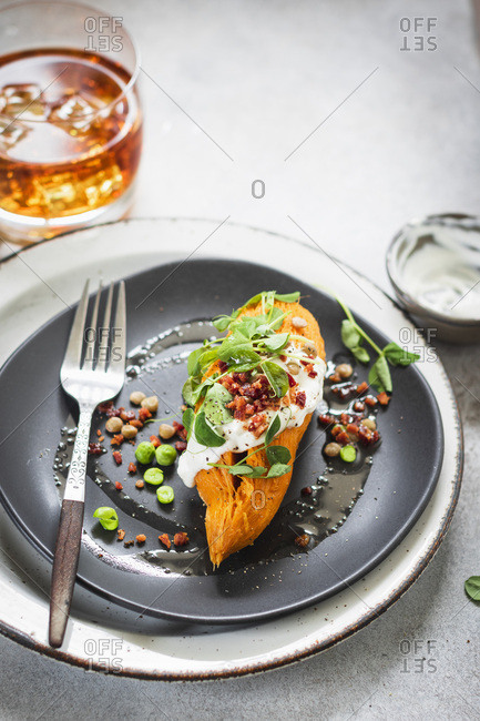 Whole baked sweet potato with sweet peas, lentils and bacon crumbs