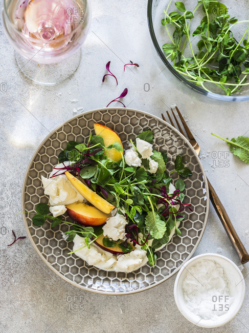 Ricotta salad with peaches and micro greens served on the gray plate