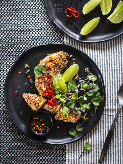 Chia Crusted Chicken Strips with micro greens served on a black plate