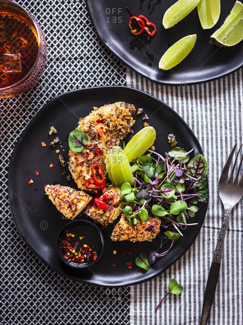 Chia Crusted Chicken Strips with micro greens served on a black plate