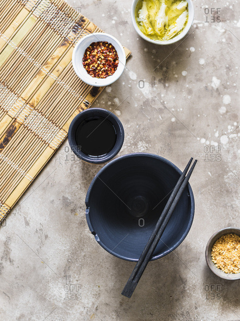 Top view on empty soup bowl, little condiment bowls and chopsticks.