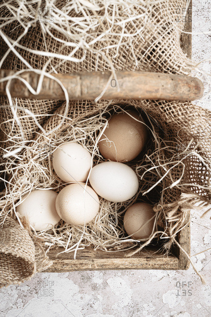 Six organic eggs into a wooden basket with straw