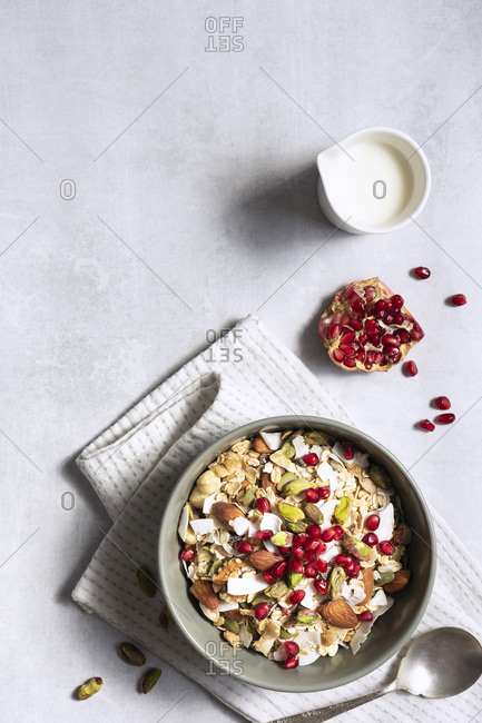 Bowl of breakfast cereal, seeds, nuts and pomegranate seeds; with copy space.