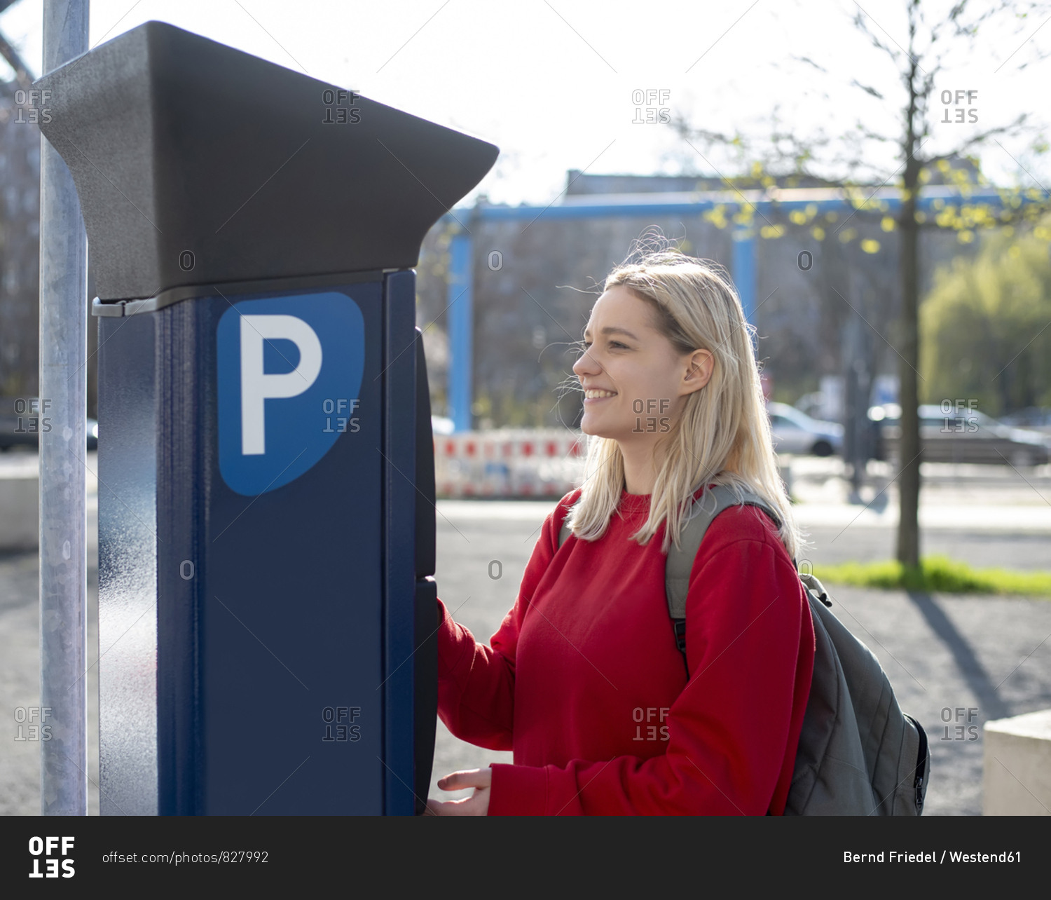 Smiling young woman using pay and display machine