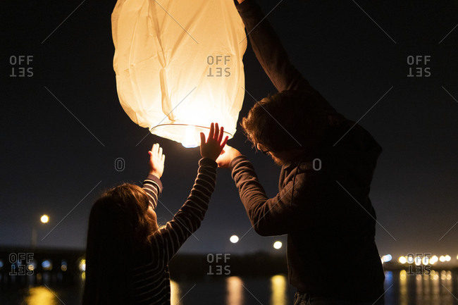 Father and daughter preparing a sky lantern on the beach at night