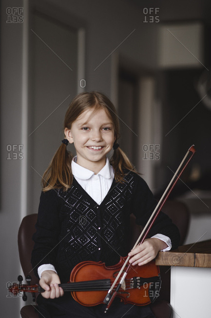 Portrait of a smiling girl with a violin at home