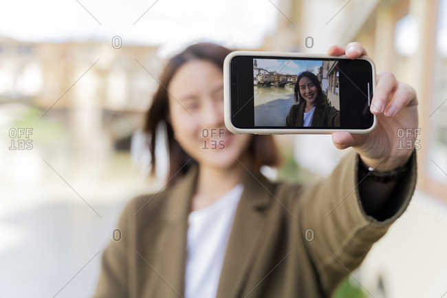 Italy- Florence- young tourist woman taking a selfie at Ponte Vecchio