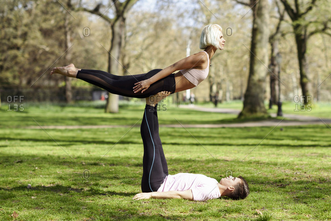 Young couple doing yoga acrobatics in an urban park