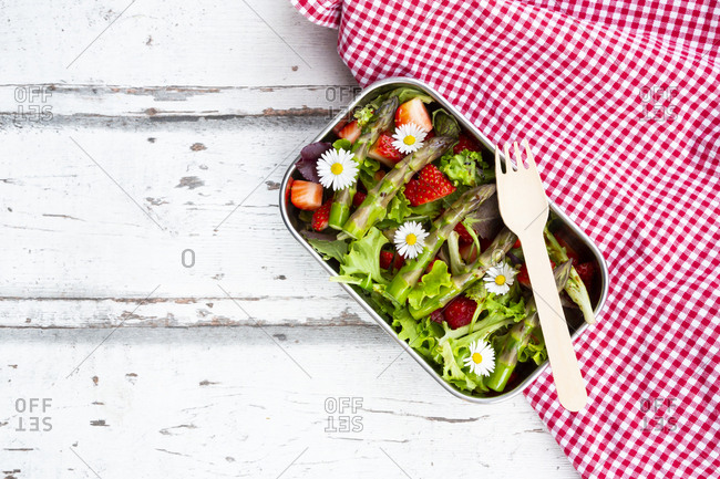Lunchbox with green salad- green asparagus- strawberries and daisies