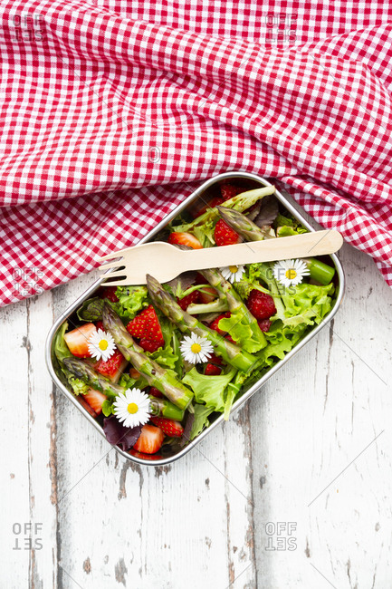 Lunchbox with green salad- green asparagus- strawberries and daisies