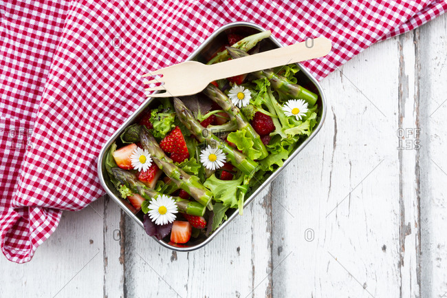 Lunchbox with green salad- green asparagus- strawberries and daisies