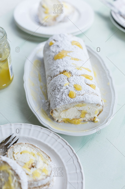 Lemon baiser roll sprinkled with icing sugar on serving plate