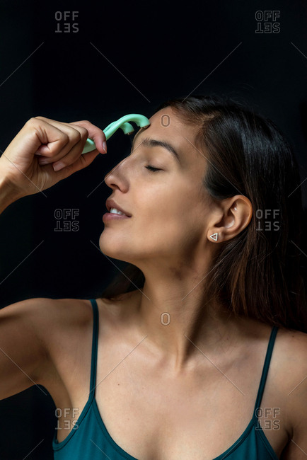 Brunette woman using a facial massager