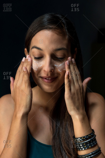 Brunette woman putting face cream