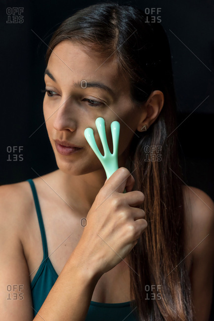 Brunette woman using a facial massager