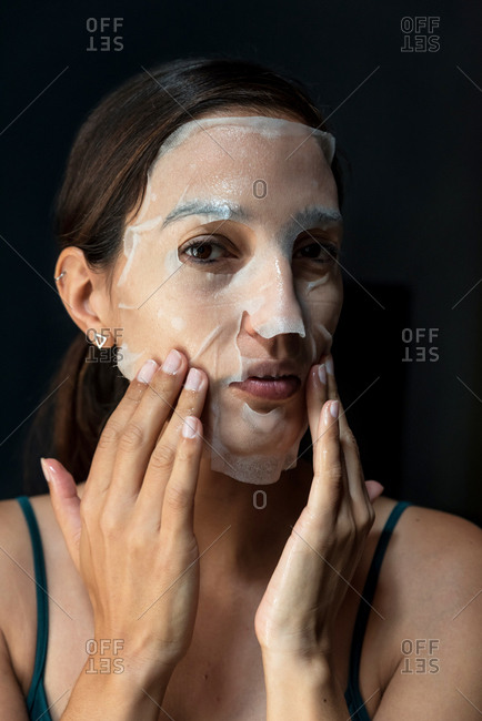 Brunette woman with a sheet moisturizing mask on her face