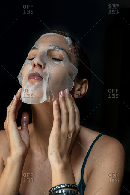 Brunette woman with a sheet moisturizing mask on her face
