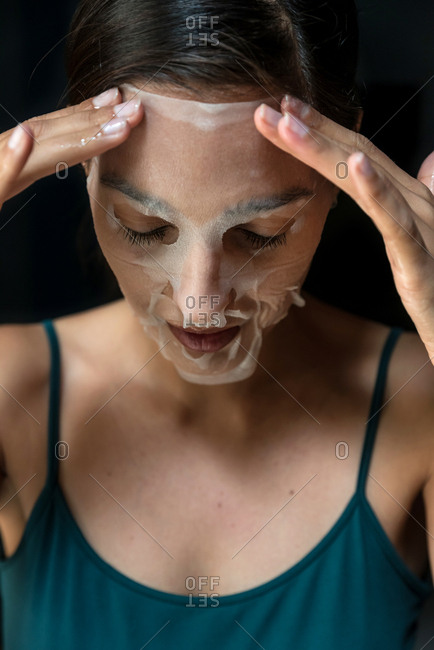 Brunette woman with a sheet moisturizing mask on her face