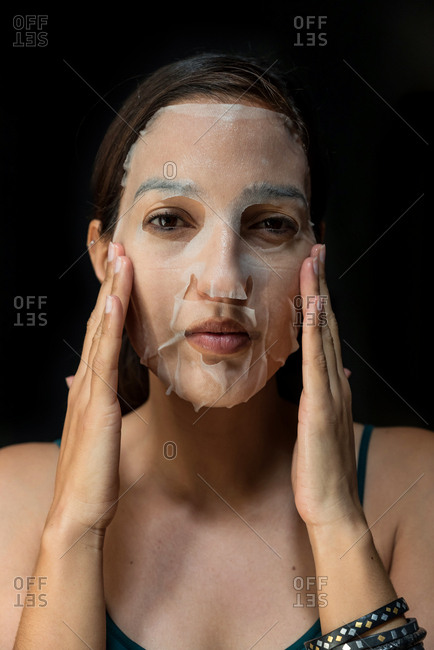 Brunette woman with a sheet moisturizing mask on her face