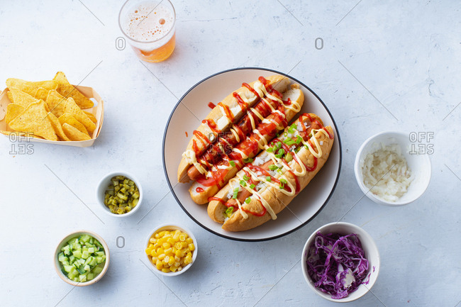 Overhead view of two hotdogs and various bowls of toppings