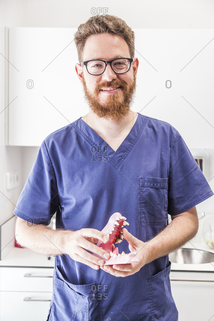 Smiling male redhead veterinarian poses with a canine dental chart in veterinary practice