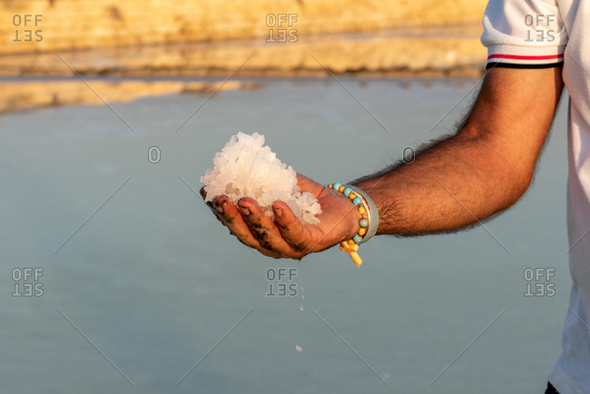 Man holding salt from salt flats in Trapani, Sicily, Italy
