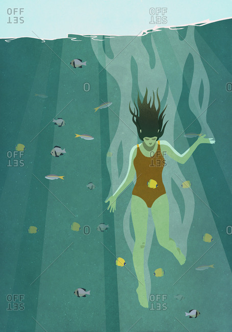 Woman diving into ocean surrounded by fish