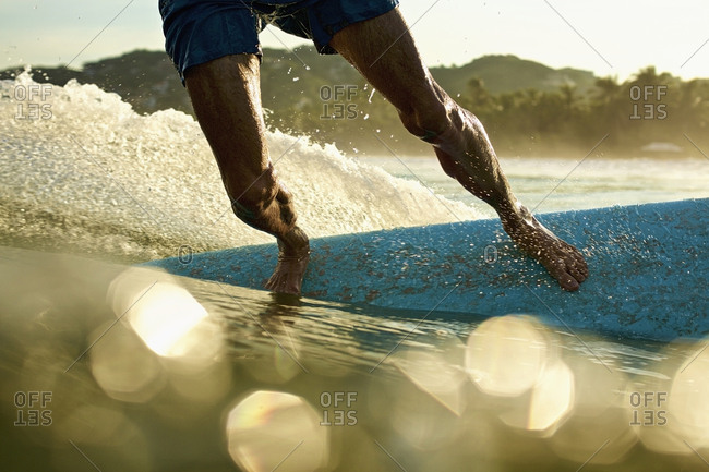 Male surfer on surfboard on sunny, sunrise ocean, Sayulita, Nayarit, Mexico