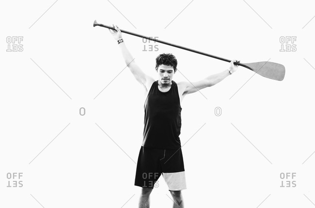 Young, fit man holding oar overhead