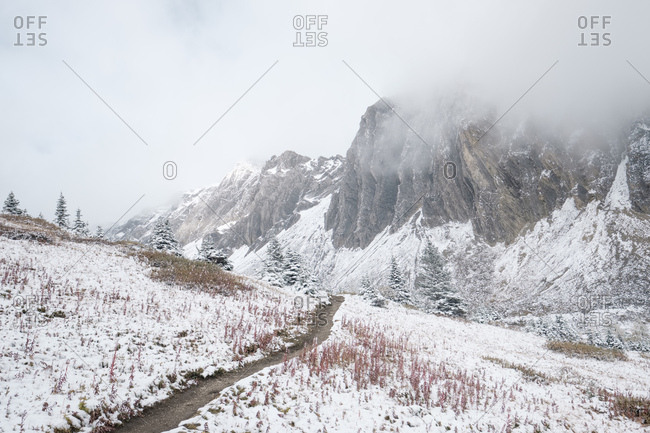 Hiking path through the first snowfall in a mountain valley