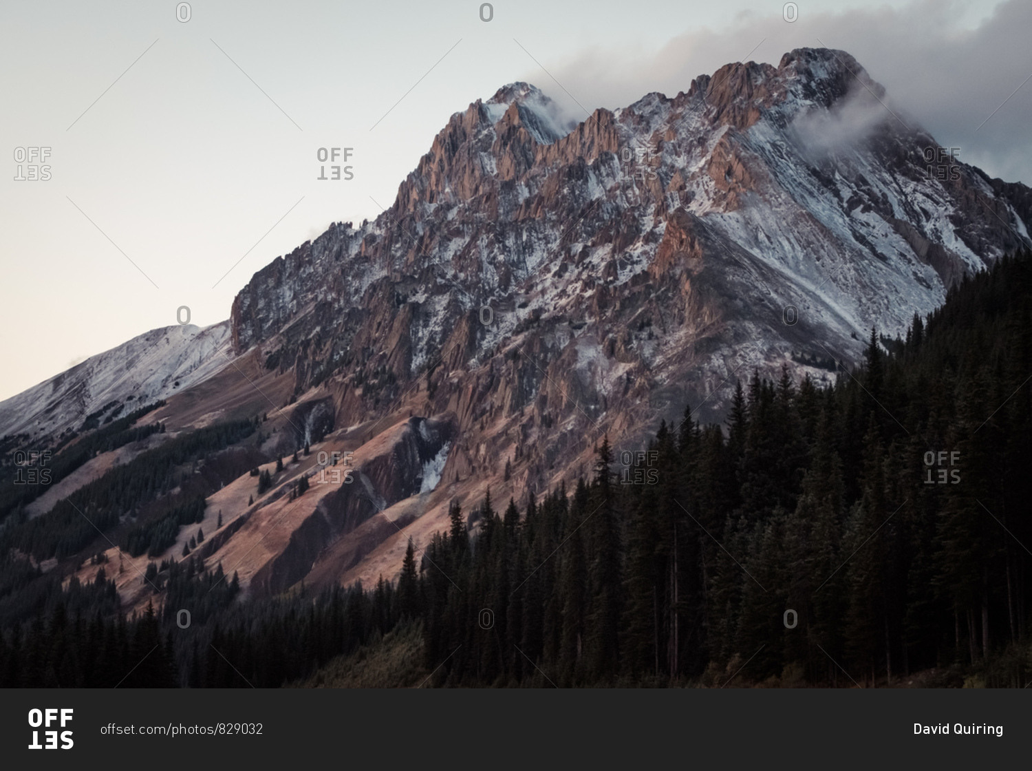 Soft evening light washes over rugged snow-kissed mountain peak