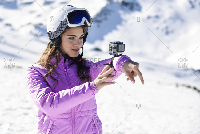 Woman in ski clothes filming with an action camera in snow covered-landscape