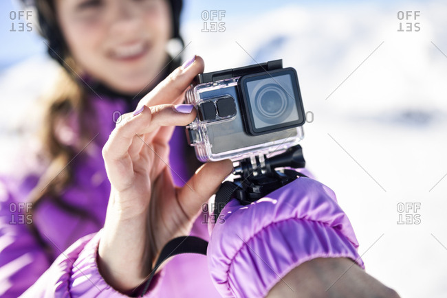 Close-up of woman in ski clothes filming with an action camera