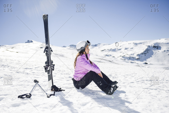 Woman taking a break after skiing sitting on the snowy ground in Sierra Nevada- Andalusia- Spain