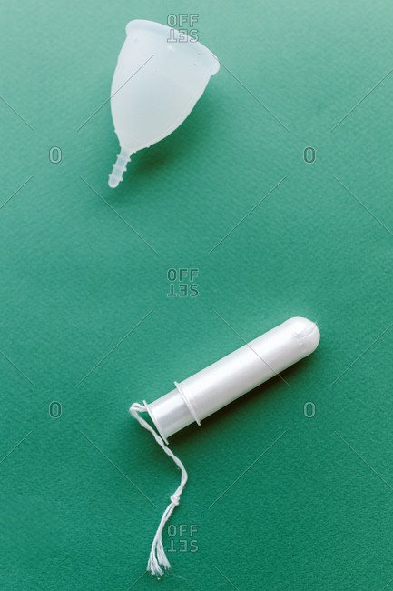Period cup and tampon on a green background