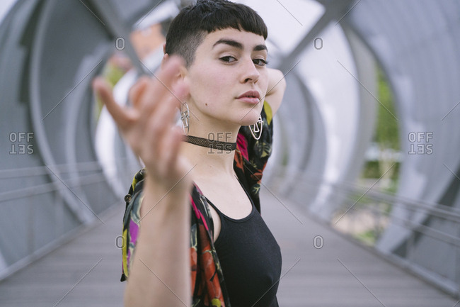 Young brunette woman in colorful shirt and black clothes posing in round tunnel and looking at camera