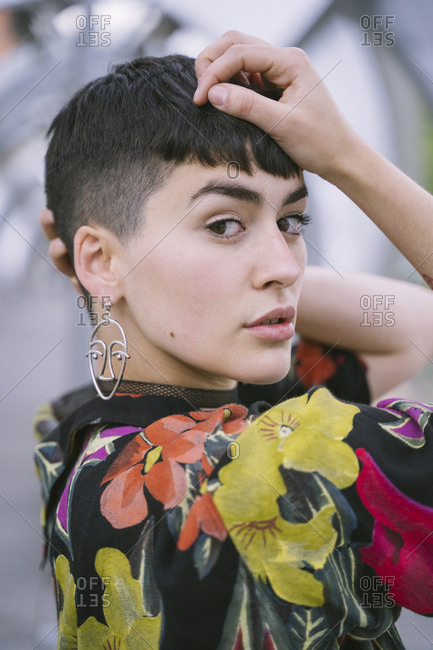 Young brunette woman in colorful shirt and black clothes posing in round tunnel and looking at camera