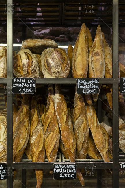 Fresh appetizing baguettes arranged on wooden rack in bakery shop
