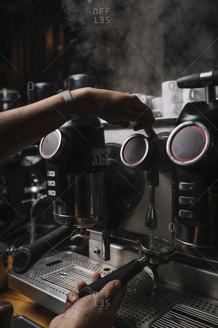 Crop hands of man making coffee by automatic professional equipment in cafe